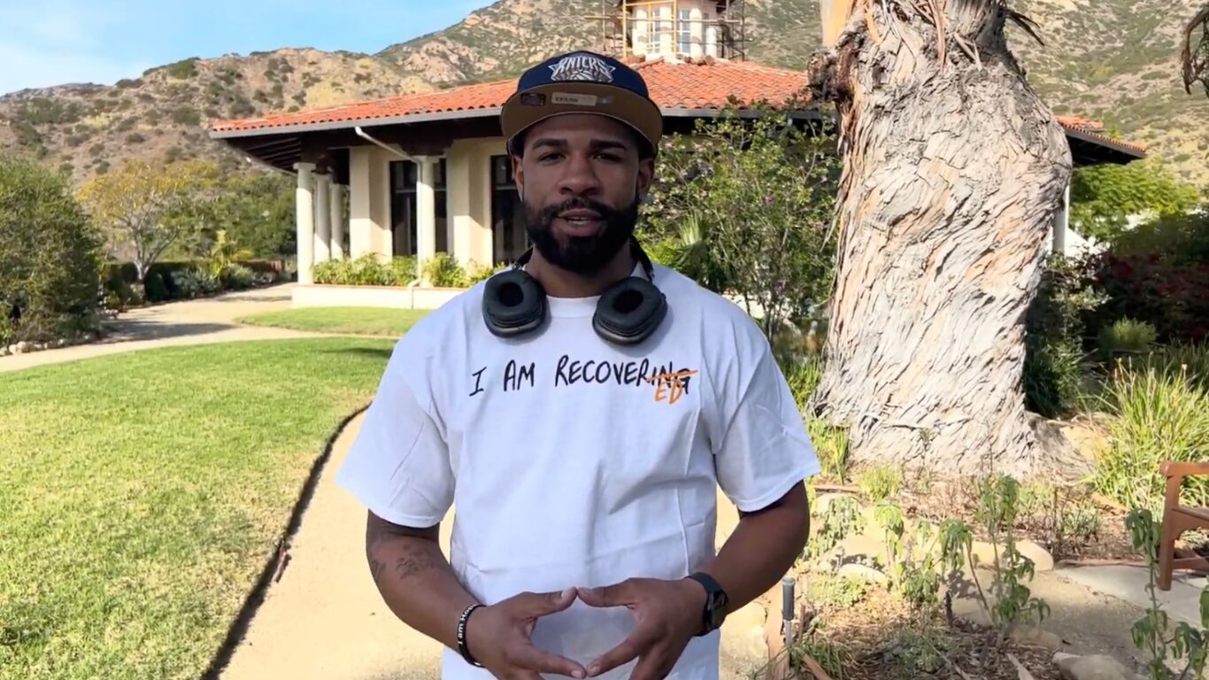 Man standing outdoors wearing headphones and recovery shirt