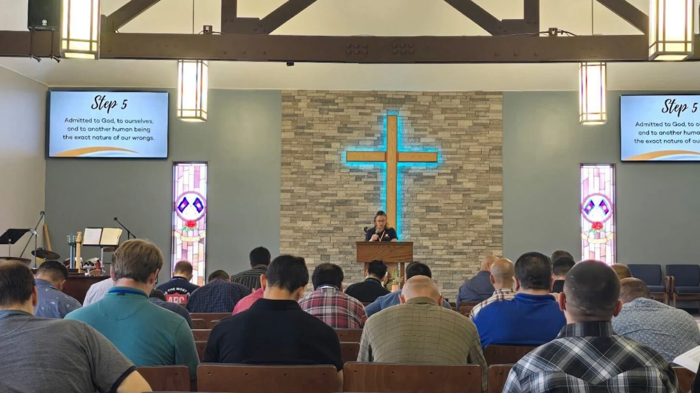 Congregation attending sermon under illuminated cross